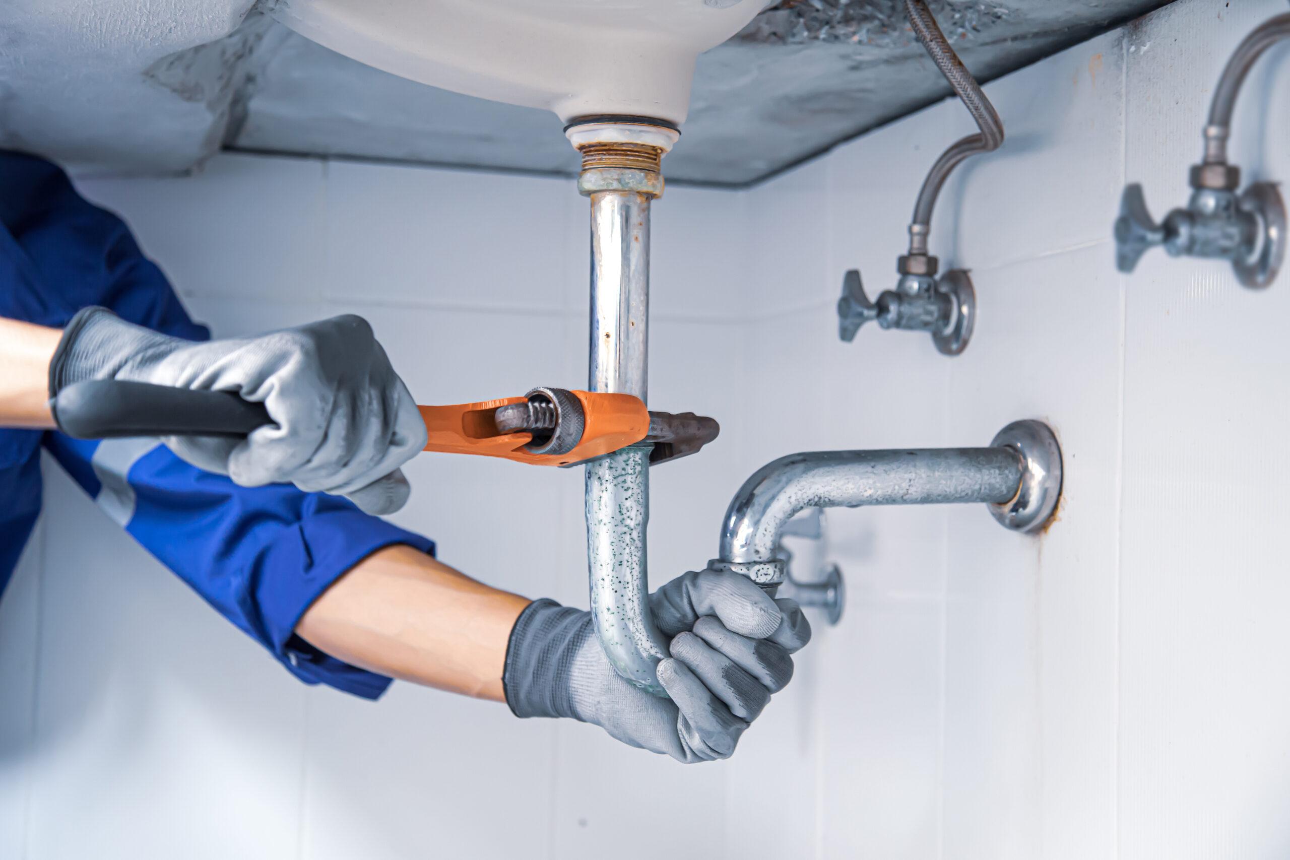 Monteur repareert een waterleiding onder de wastafel