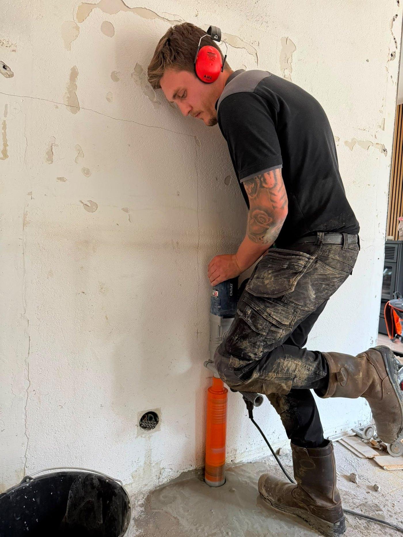 Anthony Loorbach boort een kernboring door de muur