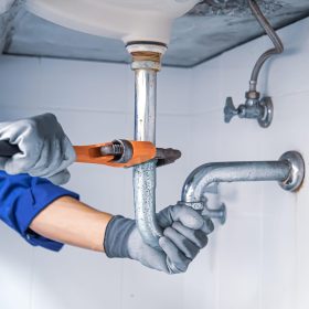 Monteur repareert een waterleiding onder de wastafel